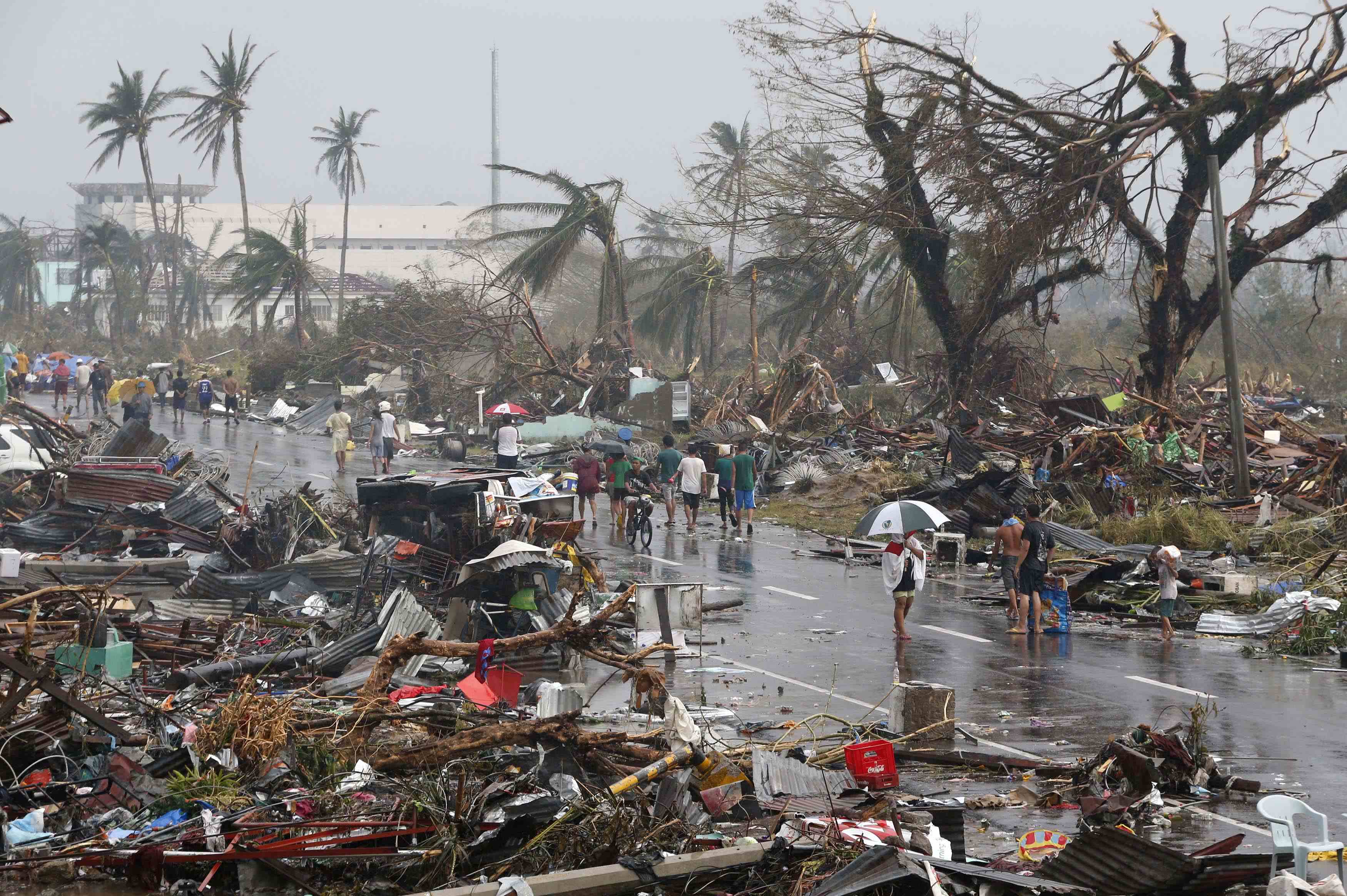 Residents walk on a road littered with debris after Super Typhoon Haiyan battered Tacloban city in central Philippines